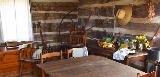 Photo inside a historic house showing a spinning wheel and a kitchen table.