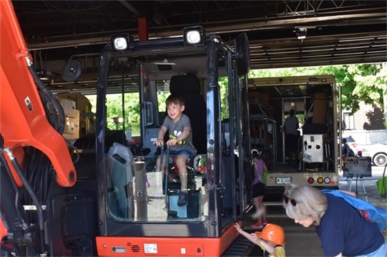 Photo of a boy sitting in a back hoe pretending to operate it at the Public Works Open House